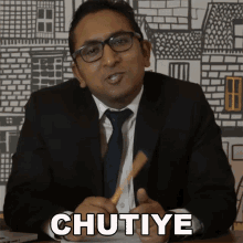 a man in a suit and tie is holding a pencil in his hand and says chutiye