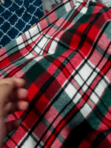 a close up of a person 's foot on a red and green plaid blanket