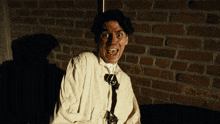 a man with blood on his face is standing in front of a red brick wall