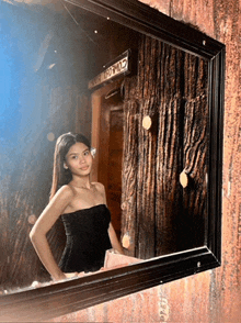 a woman is standing in front of a mirror with a sign above her that says ' a ' on it