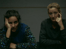 two women sitting next to each other with one wearing a blue sweater that says ' a ' on it