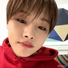 a young man wearing a red hoodie is making a face