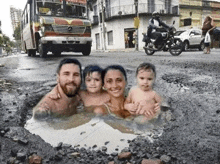 a family is taking a bath in a puddle on the side of a road .