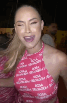 a woman wearing a pink top with the word rosa on it is smiling .