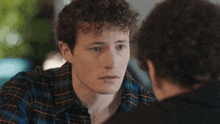a man with curly hair is looking at another man 's face