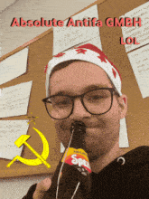 a man wearing glasses and a santa hat is drinking a bottle of absolute antifa gmbh