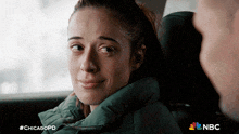 a woman in a green jacket is sitting in the back seat of a car with nbc written on the bottom