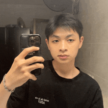 a young man taking a picture of himself in a mirror wearing a black shirt with the word vida on it
