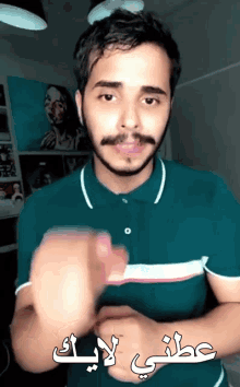 a man with a beard and mustache is wearing a green polo shirt with arabic writing on it