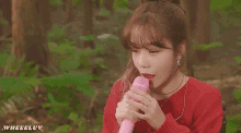 a girl in a red sweater is singing into a pink microphone while wearing ear buds