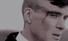 a close up of a man 's face with a bloody wound on his forehead .