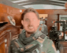 a blurry picture of a man wearing a scarf and a green jacket .