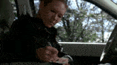 a woman is sitting in the driver 's seat of a car writing on a clipboard