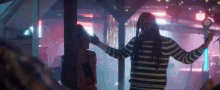 a man in a striped sweater is dancing with a woman in a club .
