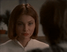 a woman with short red hair is smiling and looking at another woman