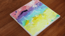 a painting with a rainbow of colors on a wooden surface