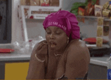 a woman wearing a pink chef 's hat is sitting in a kitchen holding a condom .