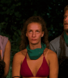 a woman in a purple bikini with a green scarf around her neck