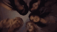 a group of women are laying in a circle with their heads on each other .