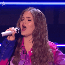a woman singing into a microphone with a star on the bottom right