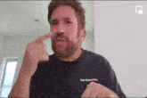 a man with a beard wearing a black t-shirt is making a funny face .