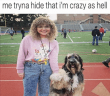a woman in a pink sweater stands next to a dog
