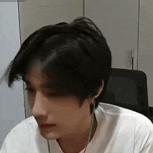 a young man wearing headphones and a white shirt is sitting at a desk .