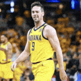 a basketball player wearing a yellow indiana jersey is walking on the court