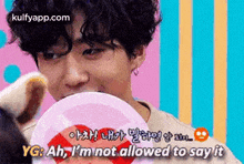 a man with curly hair is holding a heart shaped candy in his mouth while talking to a teddy bear .