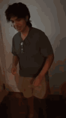 a man in a green shirt and khaki shorts is standing in a dark room .