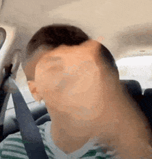 a man is making a funny face while sitting in a car with a seat belt .