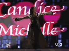 a woman stands in front of a sign that says candice michelle on it