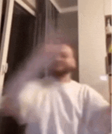 a blurry picture of a man in a white shirt standing in front of a window in a room .