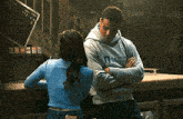 a man and a woman are standing next to each other with their arms crossed in a dark room