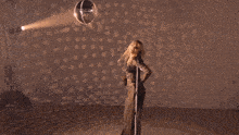 a woman singing into a microphone with her hand up