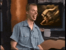 a man in a blue shirt is sticking his tongue out