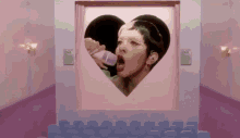 a woman is drinking from a baby bottle in a heart shaped window .
