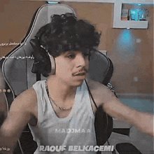 a man wearing headphones and a tank top that says madjmaa raouf belkacemi