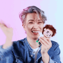 a man in a denim jacket is holding a stuffed animal in his hands