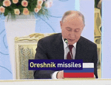 a man sits at a table with a sign that says oreshnik missiles on it