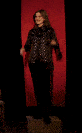 a woman is standing in front of a red curtain with her hands outstretched