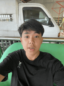 a young man sitting in front of a white truck