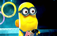 a minion wearing goggles is holding a bag of popcorn