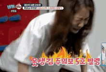 a woman in a white shirt is laying on the floor with a fire behind her in korean writing
