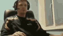 a man wearing headphones and a microphone is sitting in front of a window .