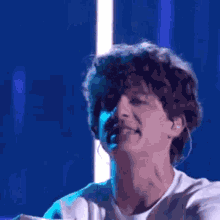 a man with curly hair is singing into a microphone on stage .