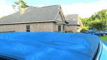 a blue tarp is covering the roof of a car in front of a brick house