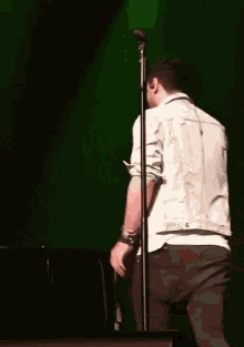 a man in a white jacket is singing into a microphone on a stage