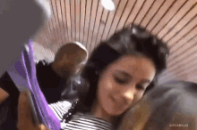 a woman in a striped shirt is holding a purple tie while a man looks on .
