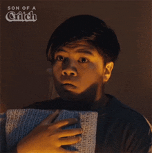 a young boy is holding a scarf in his hands and the words son of a glitch are visible behind him